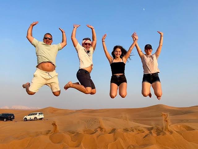 Safari vehicle driving over desert dunes